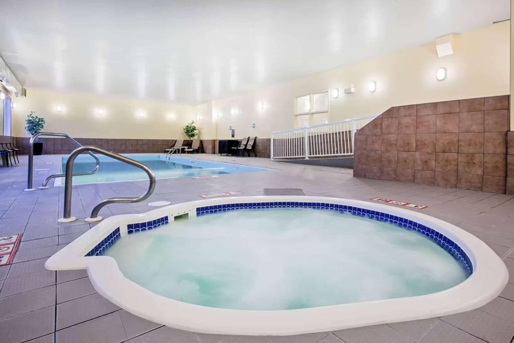 Ramada by Wyndham Prince Albert في برينس ألبرت: حوض استحمام ساخن كبير في غرفة الفندق مع مسبحين