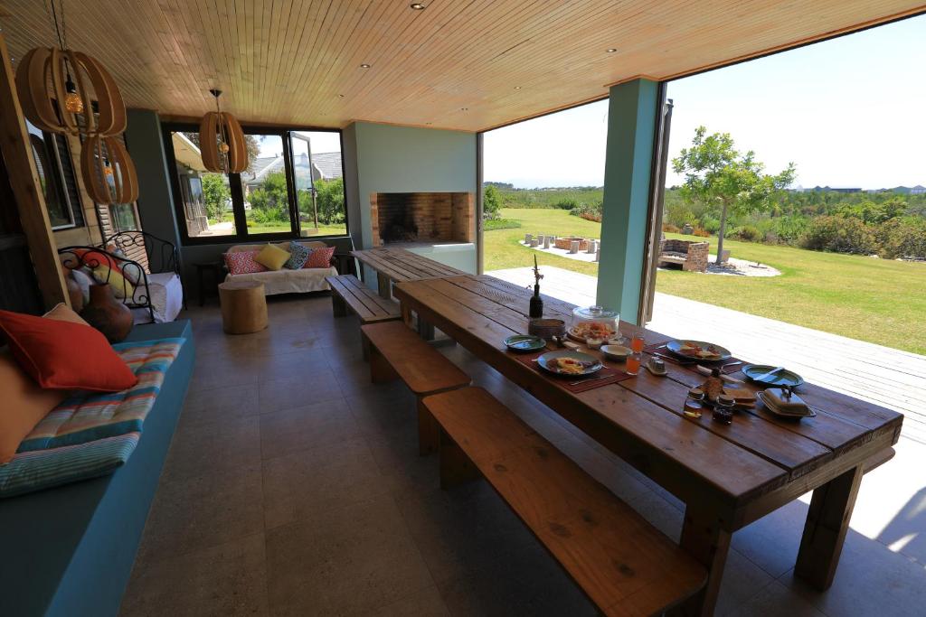 einen Holztisch im Wohnzimmer mit einem großen Fenster in der Unterkunft Gemstone Farm in Plettenberg Bay
