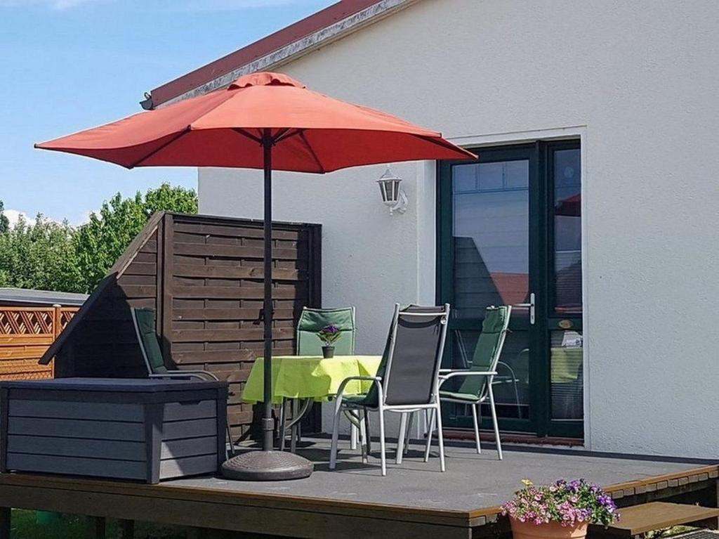 a patio with a table and a red umbrella at Strandläufer - Sünnenkieker WE11 - ABC249 in Beckerwitz