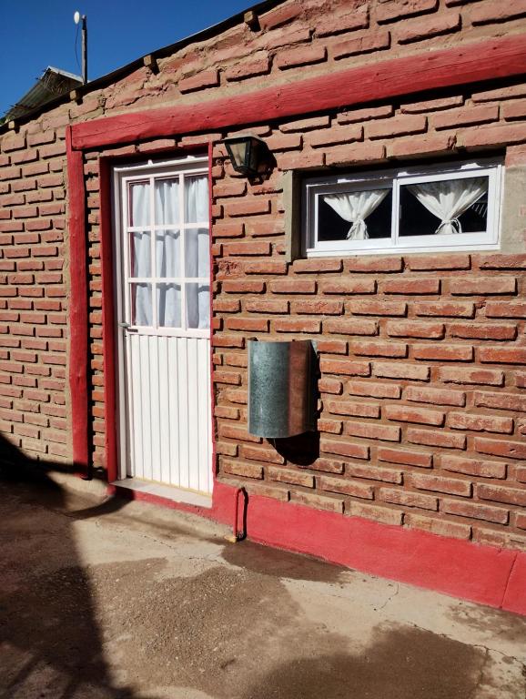 a brick building with a door and a window at Cabañas Millaray in Huinganco