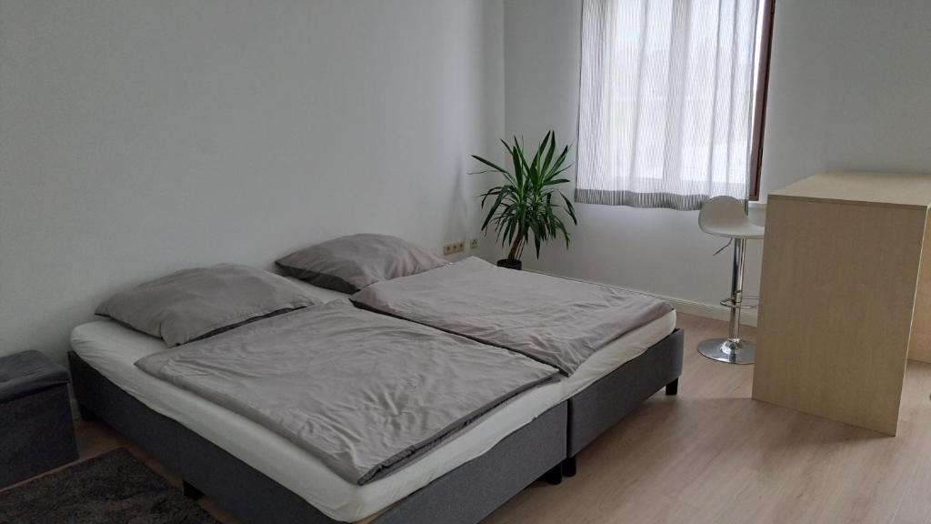 uma cama num quarto branco com uma planta em Heyerhaus Greiz em Greiz