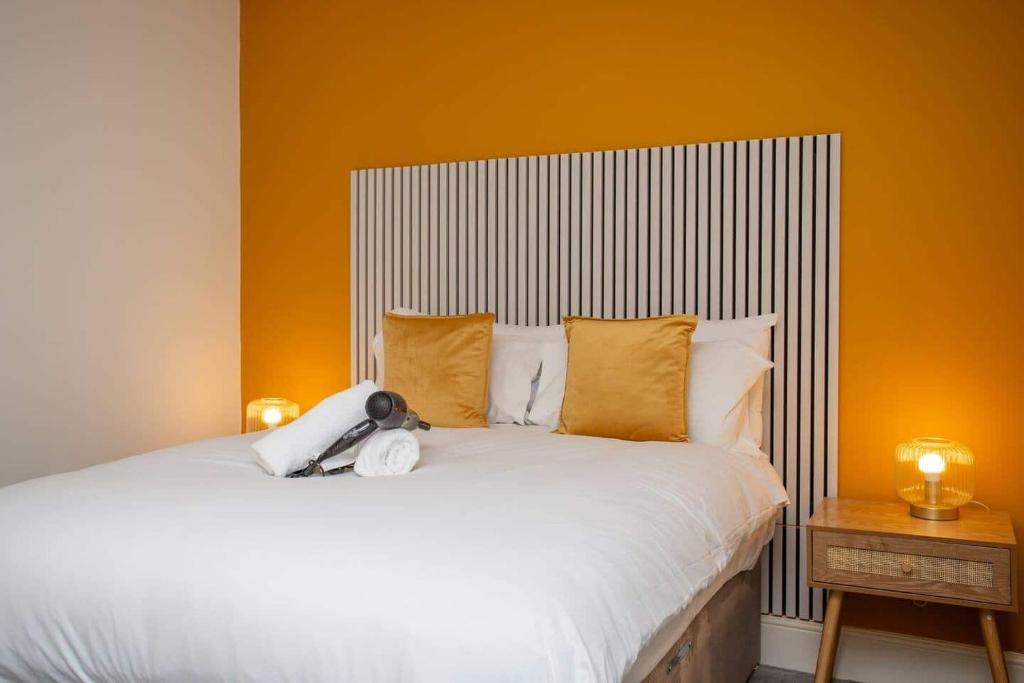 a bedroom with a white bed with an orange wall at Vacant Nests North Parade in Whitley Bay