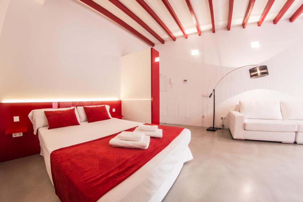 a bedroom with a red and white bed and a couch at Lonja Suites Apartments in Palma de Mallorca
