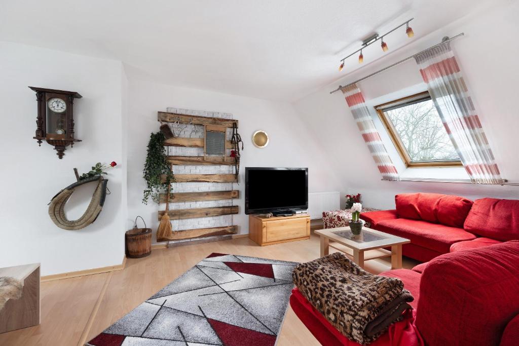 a living room with a red couch and a tv at Mole Valley Ranch Fewo1 in Elmlohe