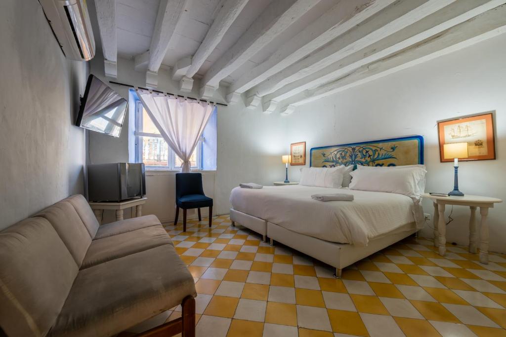 a bedroom with a bed and a couch and a tv at Casa Ámbar Cavelier in Cartagena de Indias