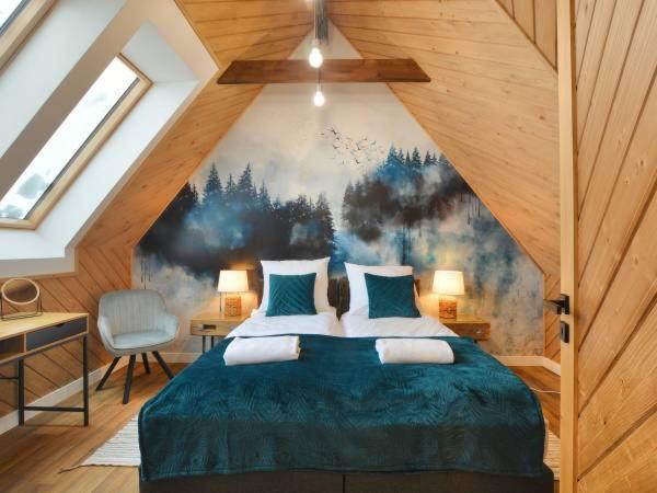 a bedroom with a blue bed with a painting on the wall at Bystre Domki in Nowe Bystre