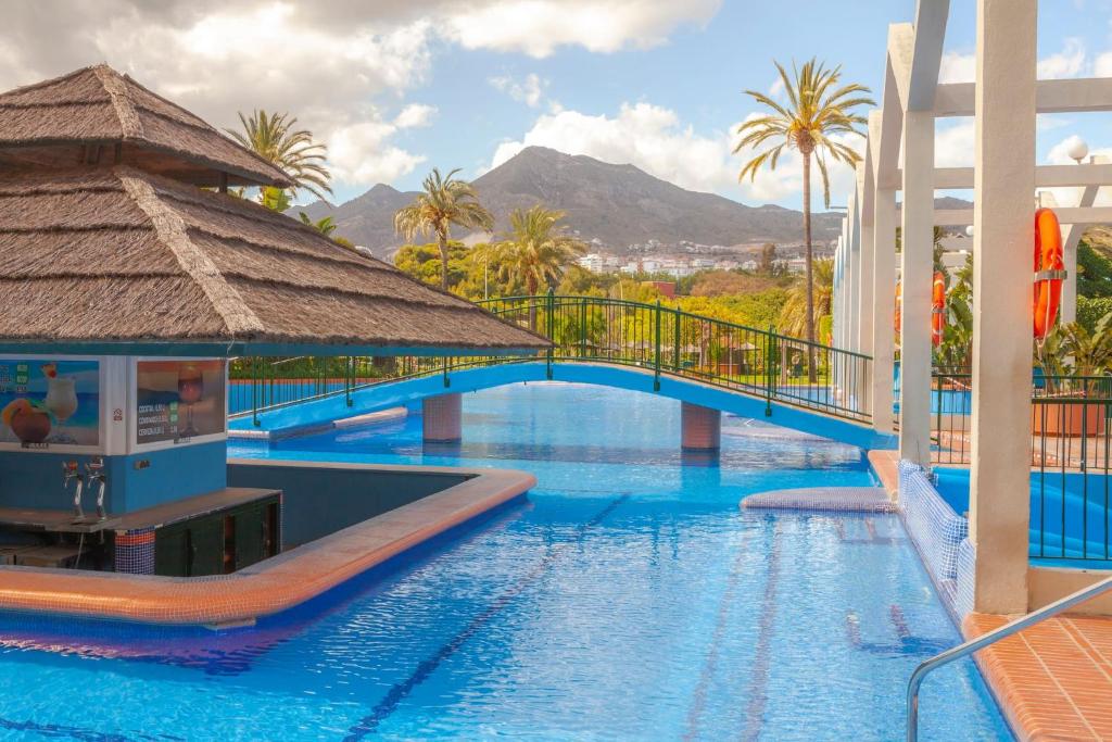 a pool at a resort with a bridge and palm trees at Luxury Condo Sea View Large Terrace BenalBeach in Benalmádena