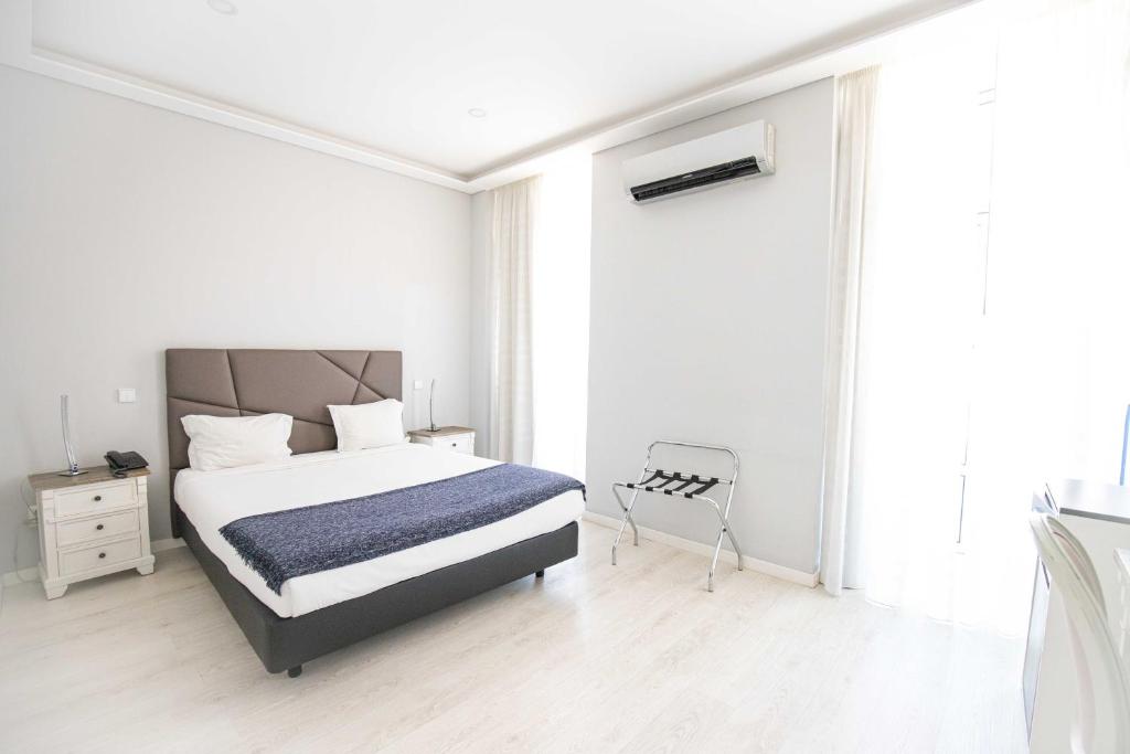 リスボンにあるグランデ ペンサオ レジデンシアル アルコビアの白いベッドルーム(ベッド1台、椅子付)