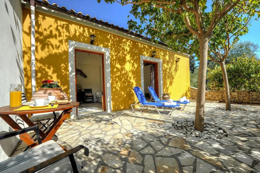 a patio with two blue chairs and a yellow building at Agathi Cottage in Longos