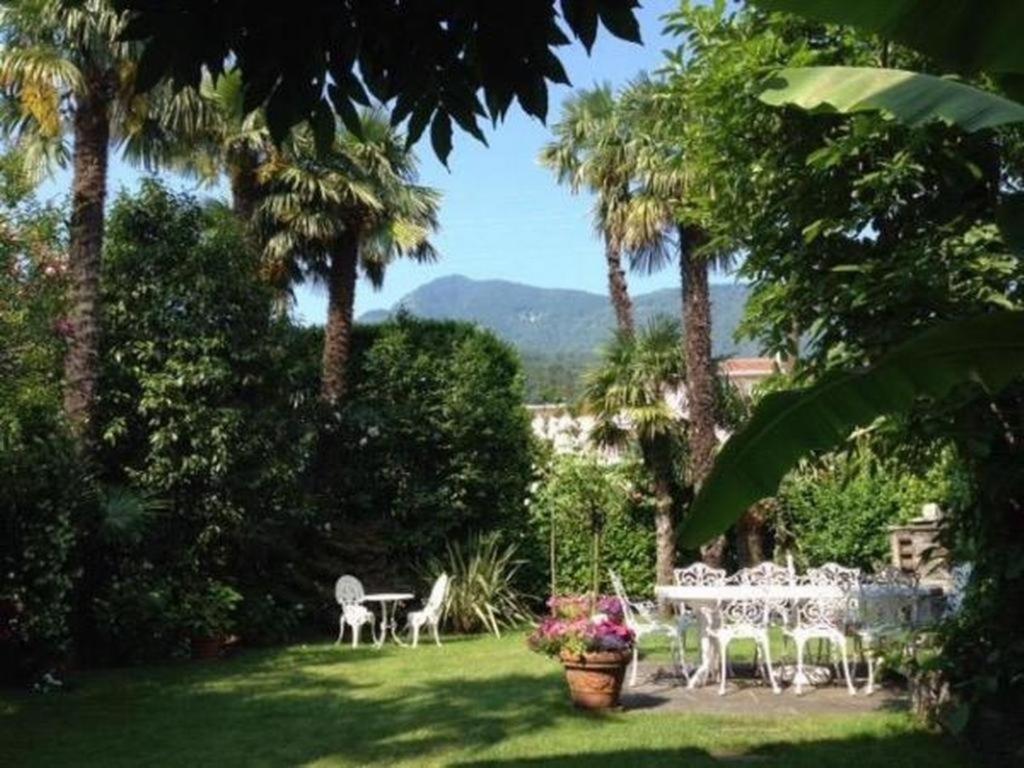 una mesa y sillas en un patio con palmeras en Casa Viola Gartenwohnung, en Losone