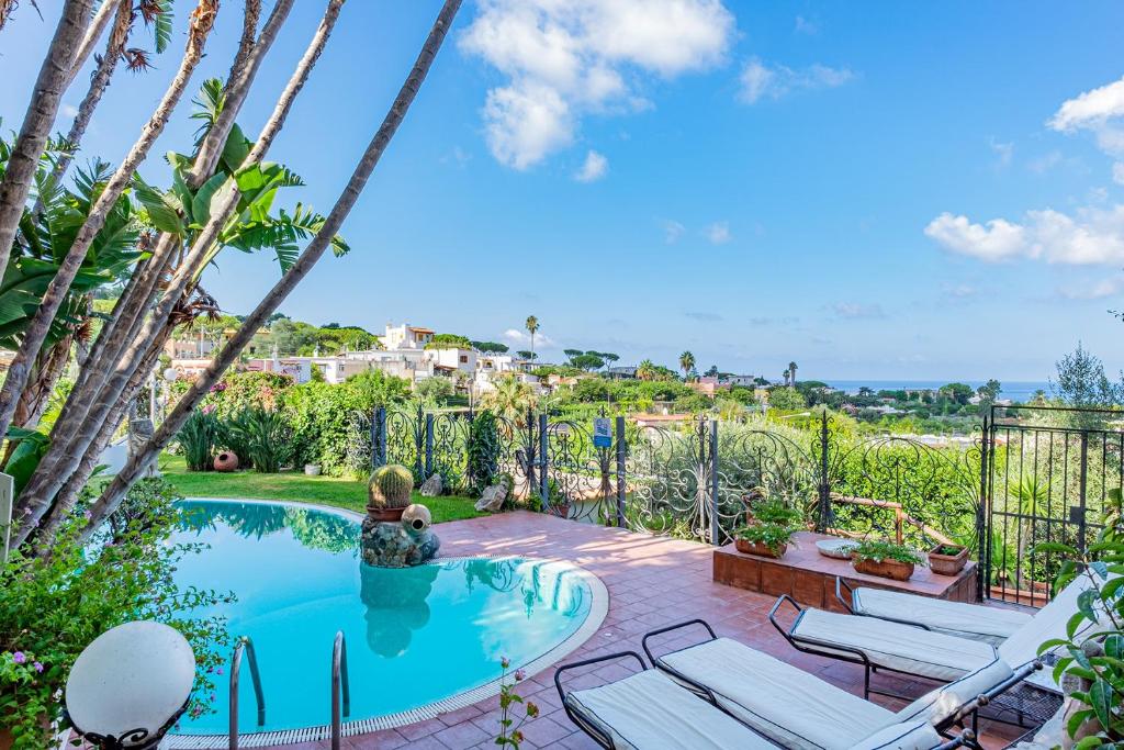 a swimming pool with chaise lounge chairs in a yard at Villa Le Palme in Ischia