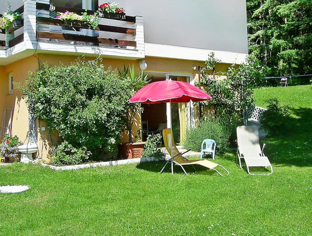 2 chaises et un parasol dans la cour d'une maison dans l'établissement Ferienwohnung Muthspiel, à Keutschach am See