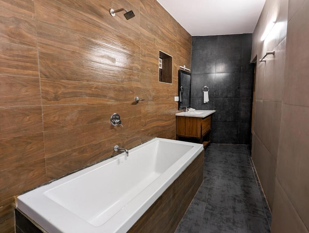 a bathroom with a large white tub and wooden walls at Seaside Serenity Resort in Mandrem