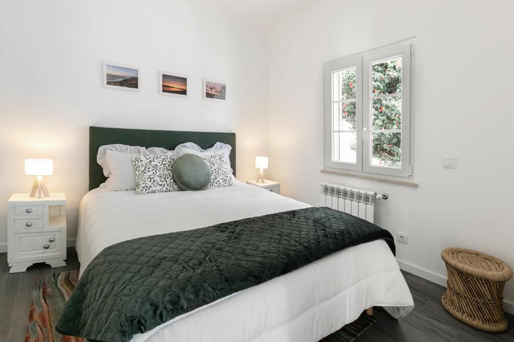 um quarto branco com uma cama grande e 2 janelas em Casa Avós Félix Lopes na Foz do Arelho