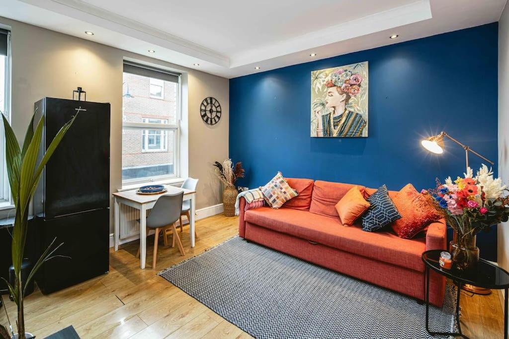 a living room with a red couch and a blue wall at Crystal Palace 2 Bedroom Flat in Crystal Palace