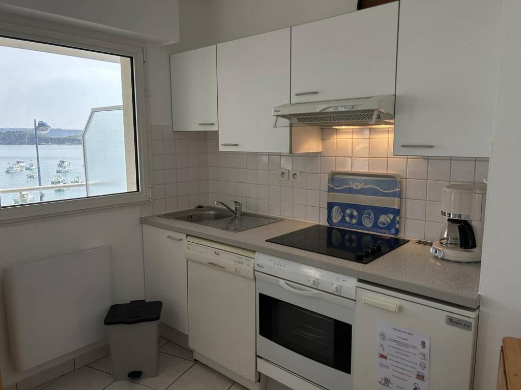a kitchen with white cabinets and a sink and a window at 501 - Appartement 1 chambre à Erquy, à proximité du port, en bordure de la plage du centre in Erquy