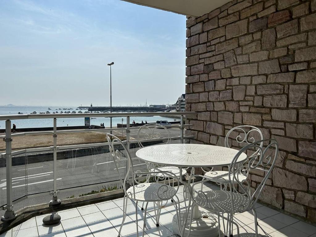 une table et des chaises sur un balcon avec vue sur l'océan dans l'établissement 504 - A Erquy, en bordure de la plage du centre, à 800m des commerces, à Erquy