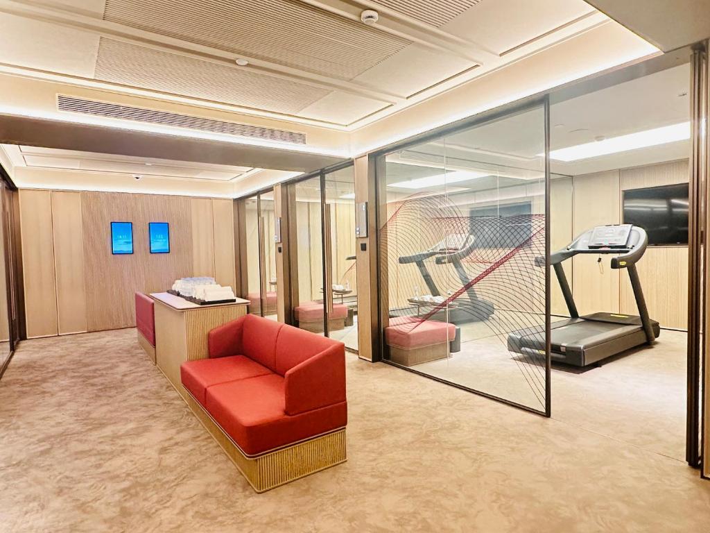 a room with a red chair and a treadmill at IntercityHotel Shanghai Hongqiao Airport - Free Minibar for First Night in Shanghai