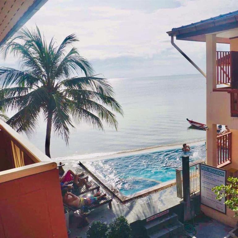 a swimming pool with a palm tree and the ocean at Rin Bay View Resort in Haad Rin