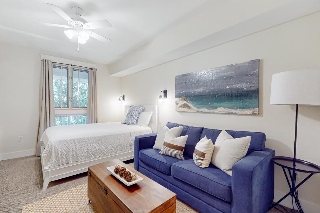 uma sala de estar com um sofá azul e uma cama em Baytowne Wharf - Pilot House #207 em Destin