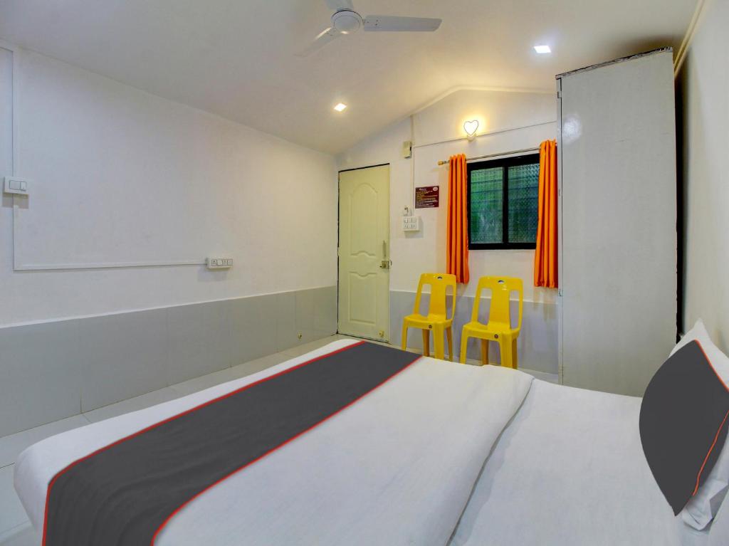 a bedroom with a bed and two yellow chairs at Homely Stays Resort in Pune