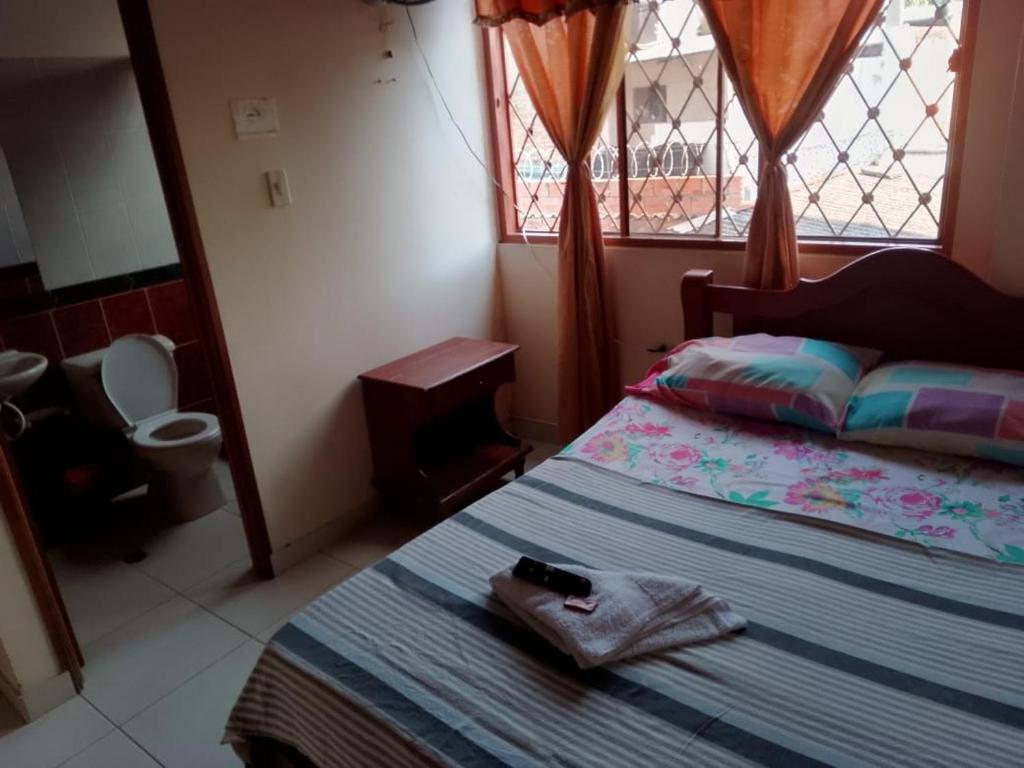 a bedroom with a bed and a window with a toilet at Samantha Hotel in Paz de Ariporo