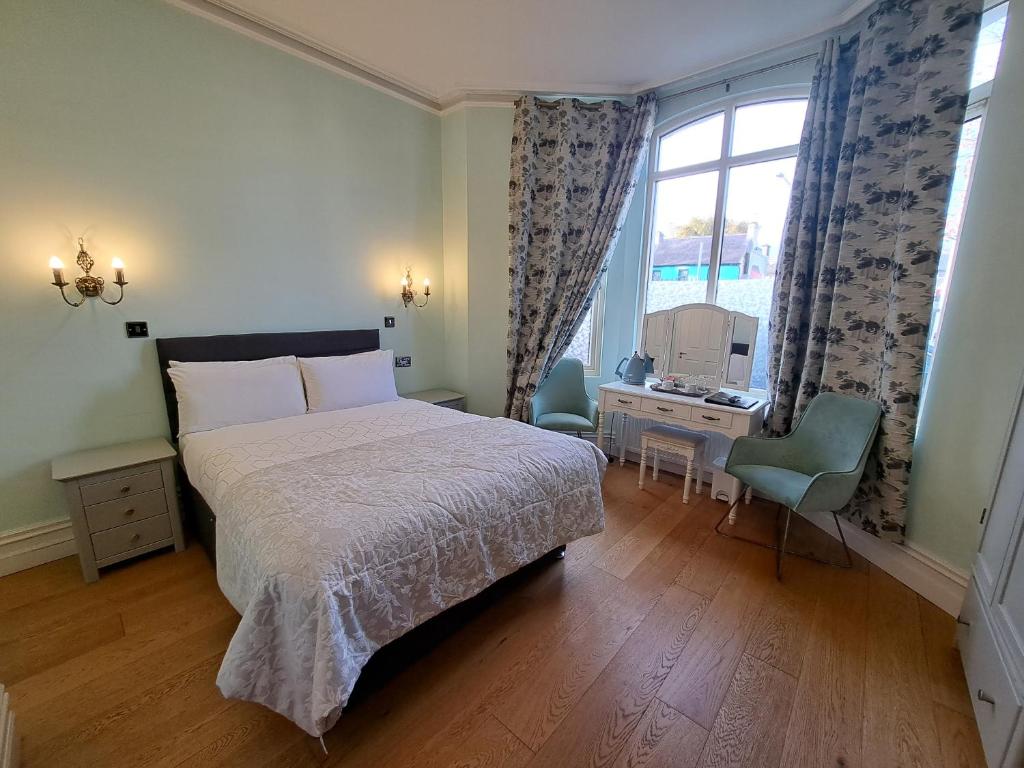 um quarto com uma cama, uma secretária e uma janela em Shandon Bells Guest House em Cork