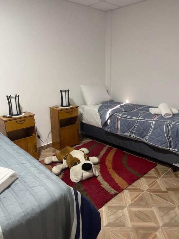 a bedroom with two beds and a stuffed dog laying on the floor at MAGU in Malargüe