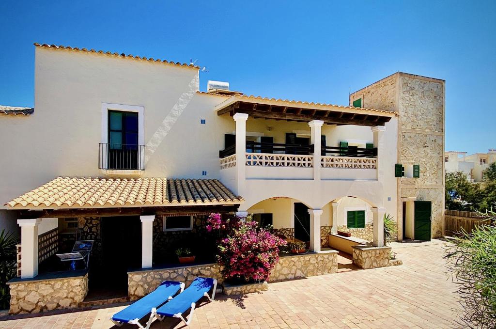 a house with two blue chairs in front of it at Apartments Campanitx - Astbury Formentera in Es Caló