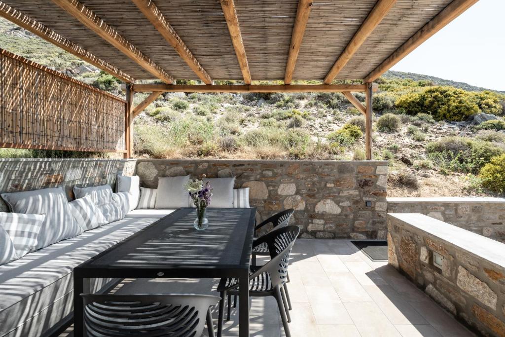 a table and chairs on a patio with a wooden roof at Ammoa Beach Residences in Vayiá