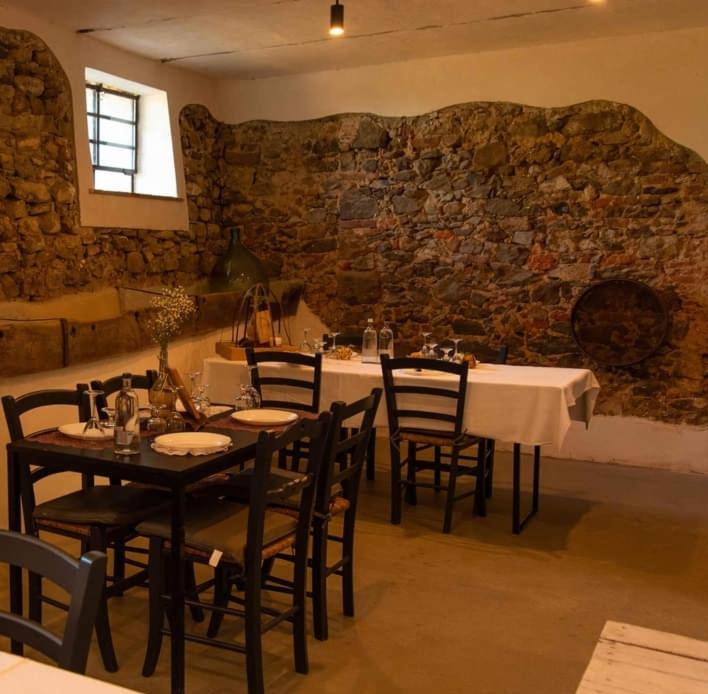 Azienda agricola Scerba في Montemagno: غرفة طعام بها طاولات وكراسي وجدار حجري