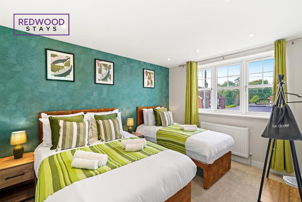 duas camas num quarto com paredes verdes em BRAND NEW! Modern Houses For Contractors & Families with FREE PARKING, FREE WiFi & Netflix By REDWOOD STAYS em Farnborough