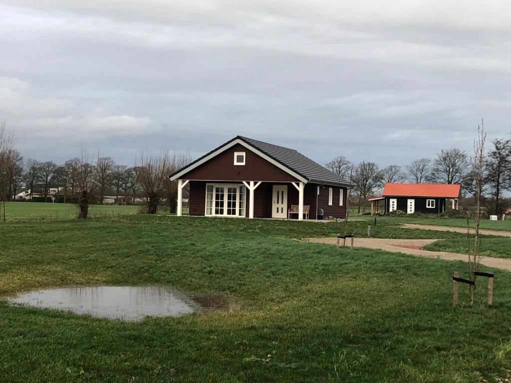 een huis in een veld met een plas in het gras bij triphousing red in Schalkwijk