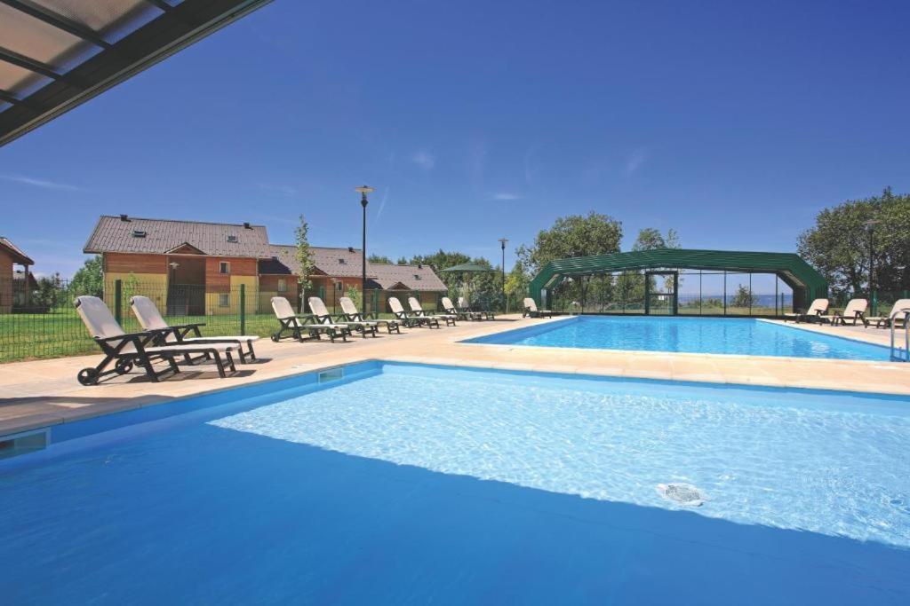 Duplex-Chalet entre Lac et Montagne avec Balcon في لوجْرا: مسبح كبير مع كراسي بجوار منزل