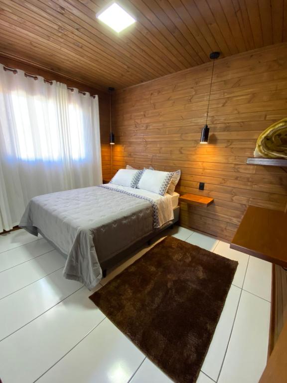 a bedroom with a bed and a wooden wall at Aconchego Alto da Serra in Barracão