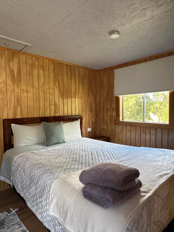 a bedroom with a bed with towels on it at Cabañas Kuyén Austral in Hornopiren