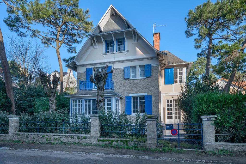 una casa con ventanas azules y una valla en Belle villa bauloise à deux pas de la plage, en La Baule
