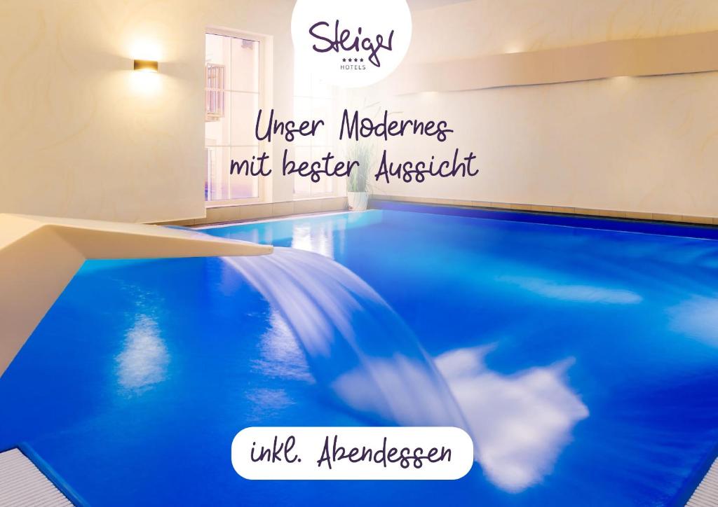 Ein Pool mit blauem Wasser und die sprachliche Vielfalt der Sitzungen in der Unterkunft STEIGER Hotel Rathener Hof in Kurort Rathen