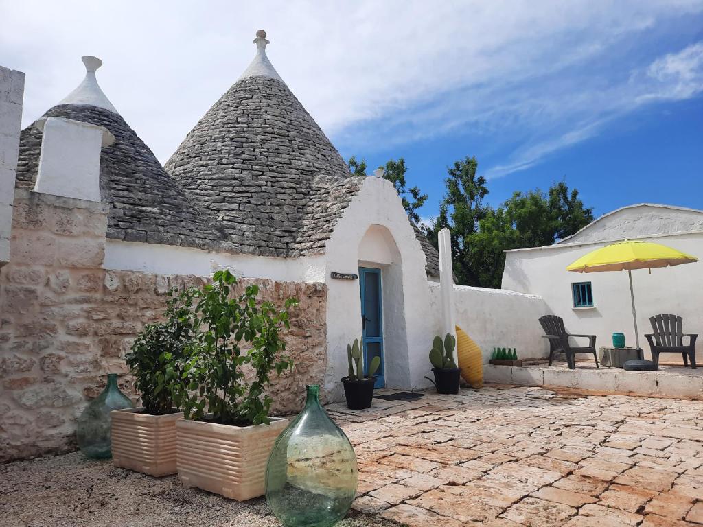 Casa con patio de piedra con plantas y sombrilla en Casa Trullo Bianco: Casa Limone, en Ceglie Messapica