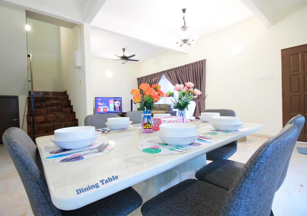 a white table with chairs and bowls and flowers on it at H2H - Bintang49 Vacation House in Ipoh