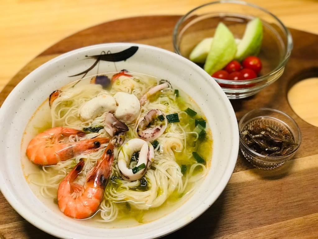 a bowl of soup with shrimp and noodles on a table at Yurong B&B in Magong
