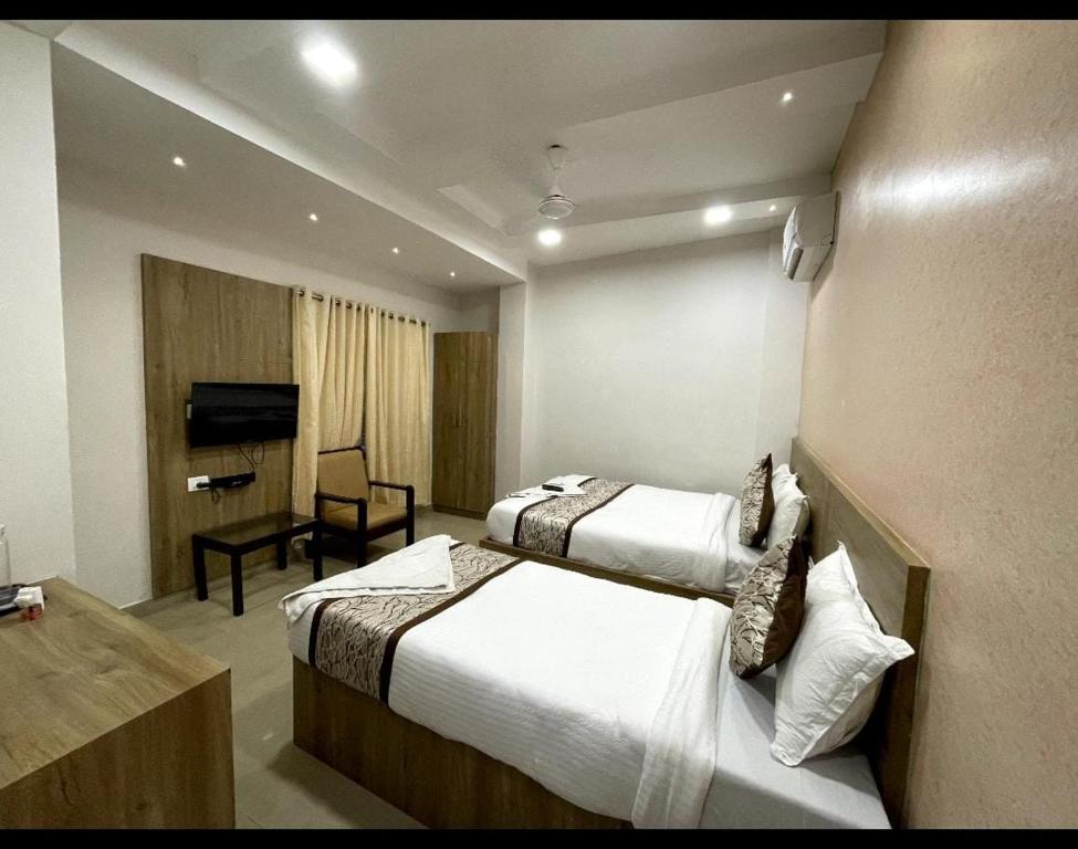 Cette chambre comprend deux lits et une télévision. dans l'établissement GREEN TERRUS BUSINESS CLASS HOTEL, à Chennai