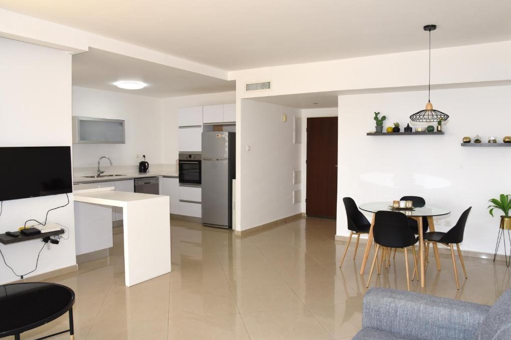 a kitchen and living room with a table and chairs at Stylish 3BR Golf Residence Eilat in Eilat