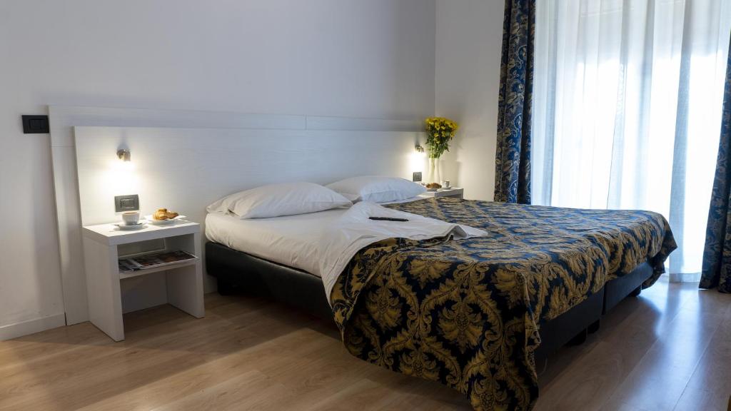 a bedroom with a large bed with a nightstand and a bed sidx sidx sidx at Hotel Rex Milano in Milan