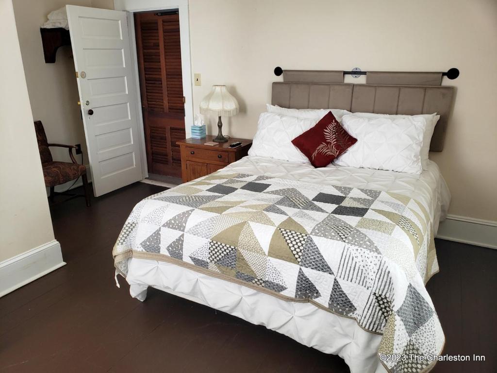 een slaapkamer met een bed met een zwart-witte quilt bij The Charleston Inn Hendersonville NC in Hendersonville