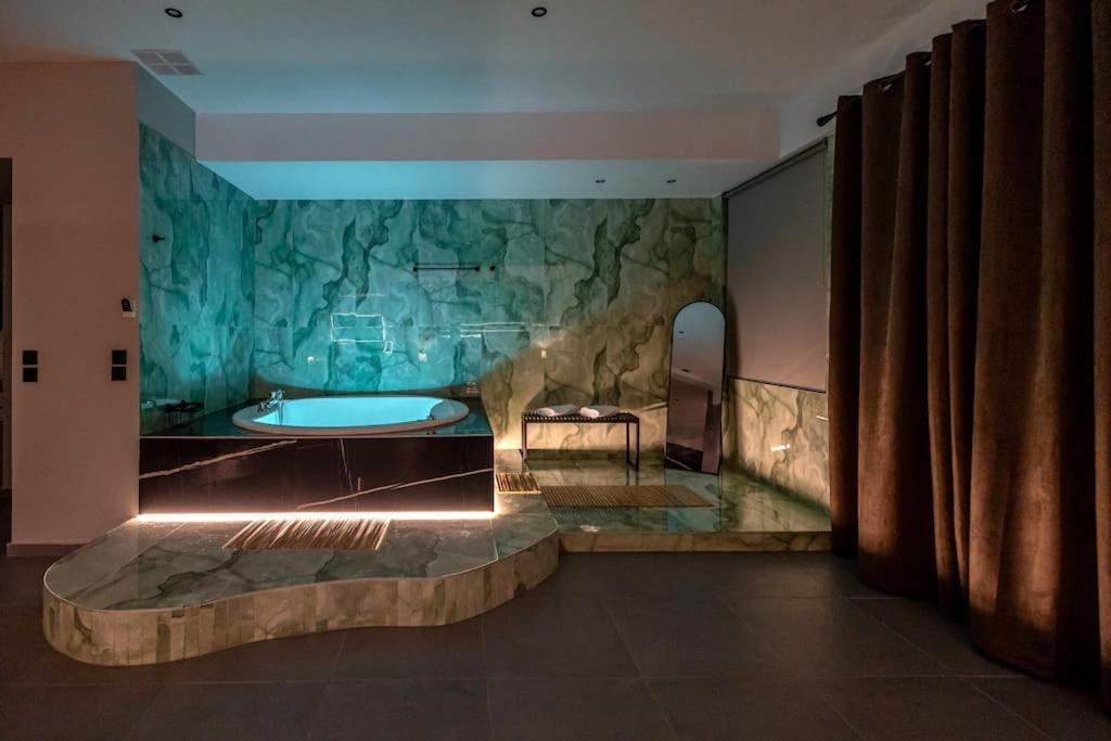 baño con bañera y pared de piedra en Smaragdi Luxury Jacuzzi Apartment Noho Premium Living en Athens