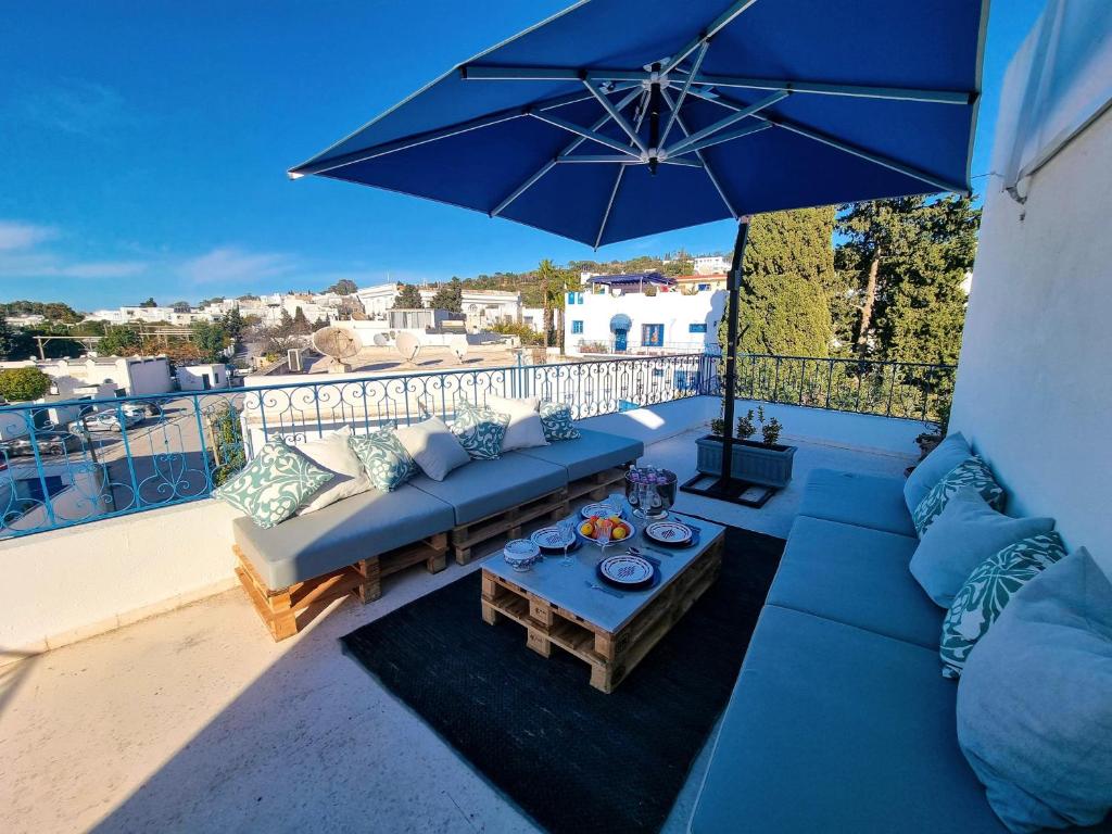 un sofá azul y una mesa con sombrilla en el balcón en Le Superbe - Sidi Bou Saïd, en Dar Mimoun Bey