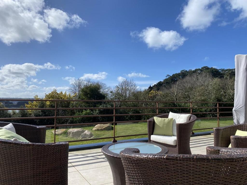 d'une terrasse avec des chaises en osier et une table sur un balcon. dans l'établissement 662 - Grande et Magnifique maison vue mer pour séjour en famille, à Erquy
