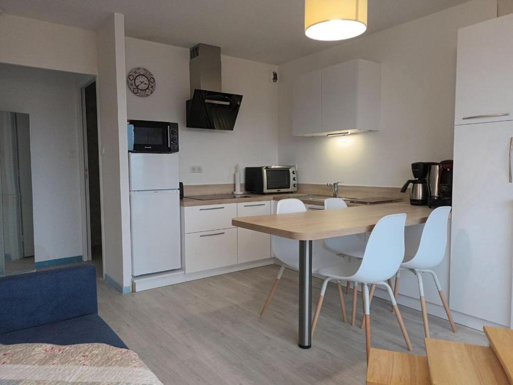 eine Küche mit einem Tisch und Stühlen im Zimmer in der Unterkunft 664 - Bel appartement à Erquy, à 400m de la plage du centre offrant une vue en hauteur du Port in Erquy