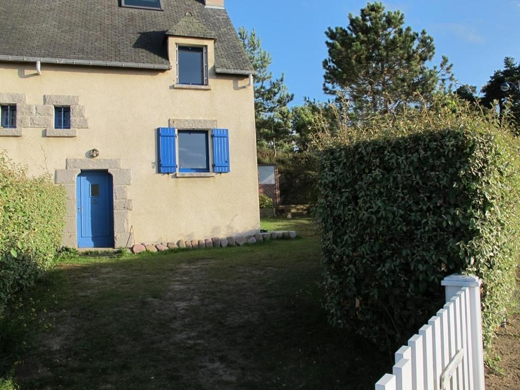 une maison avec une porte bleue et une haie dans l'établissement 700 - Charmante maison A ERQUY, Domaine privé de LANRUEN face à la plage, à Le Val